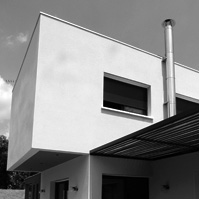 Espace repas sur la terrasse extérieure protégée du soleil par une pergola métal et bois. Conduit de fumée extérieur en inox.<br />